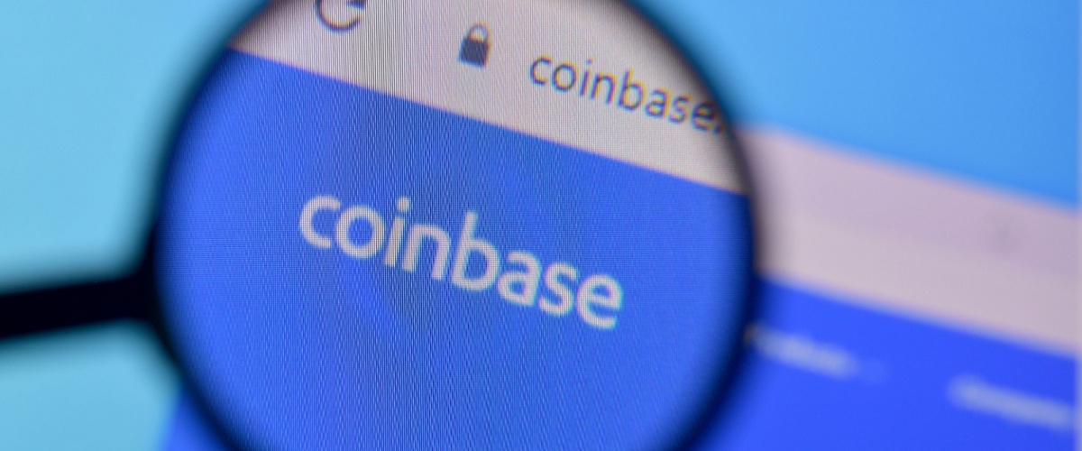 The coinbase website on a desktop computer, magnified by a magnifying class