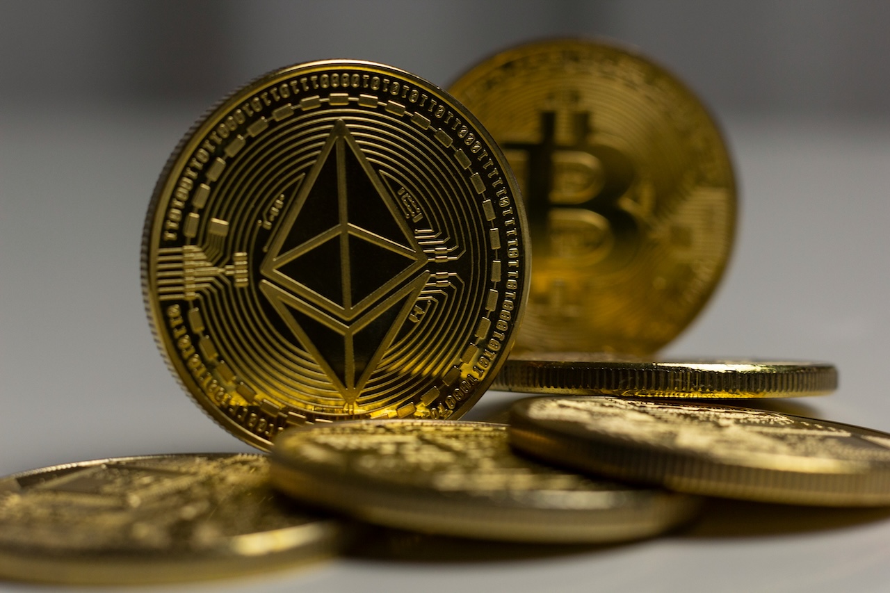 A photo of physical Ethereum and Bitcoin coins. According to Standard Chartered, Ethereum treasuries have the potential to outperform Bitcoin in 2025.